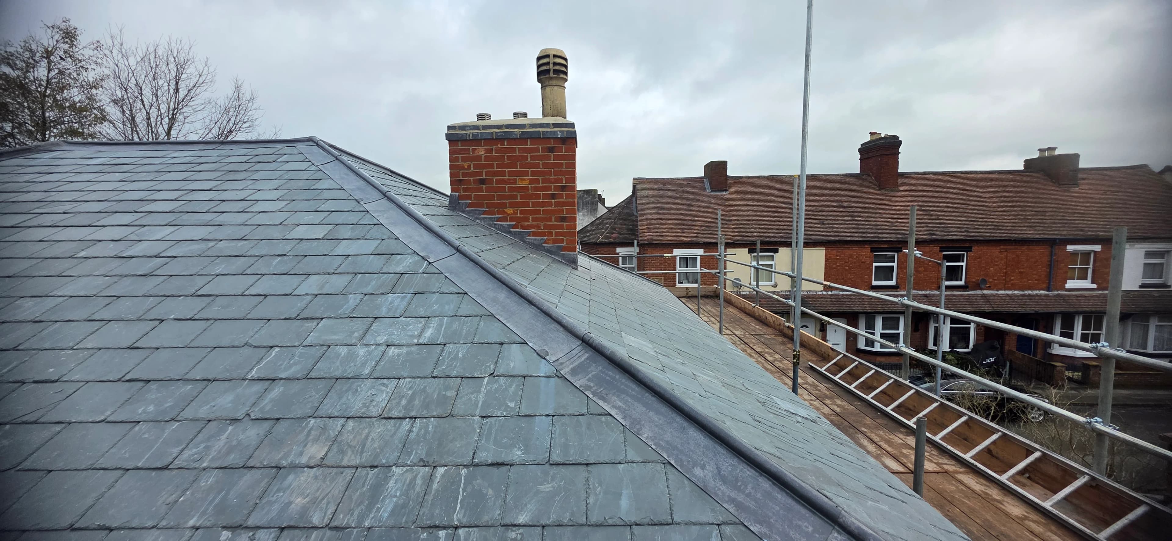 Grey slate roof with houses beyond after completion