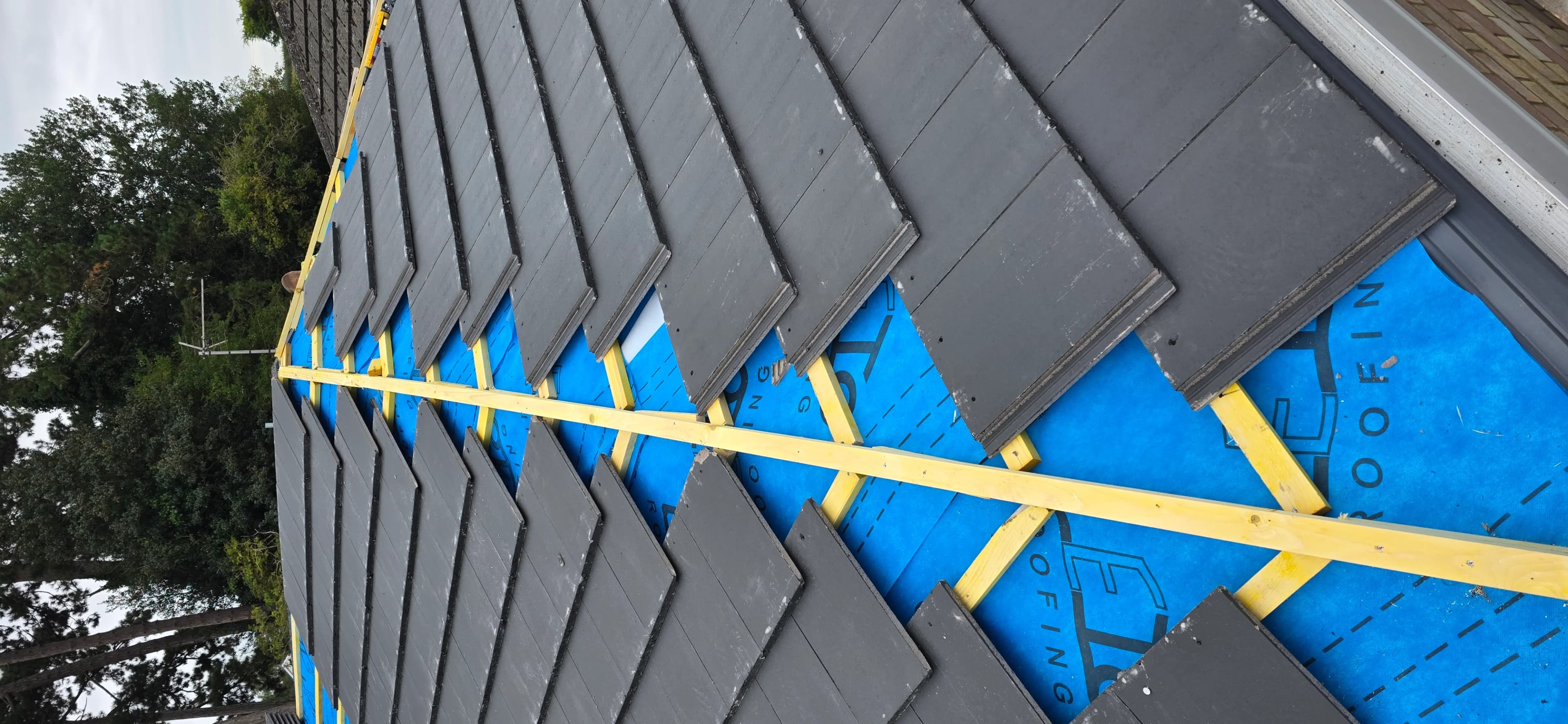 Grey tiles being laid over a blue breathable membrane