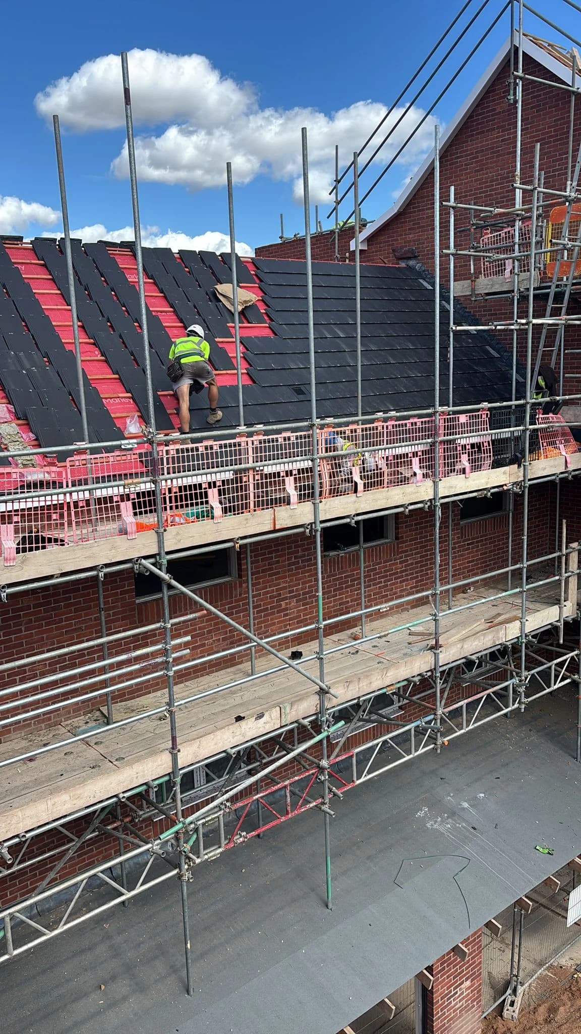 Roofers in hi-vis working safely on a large roof with membrane