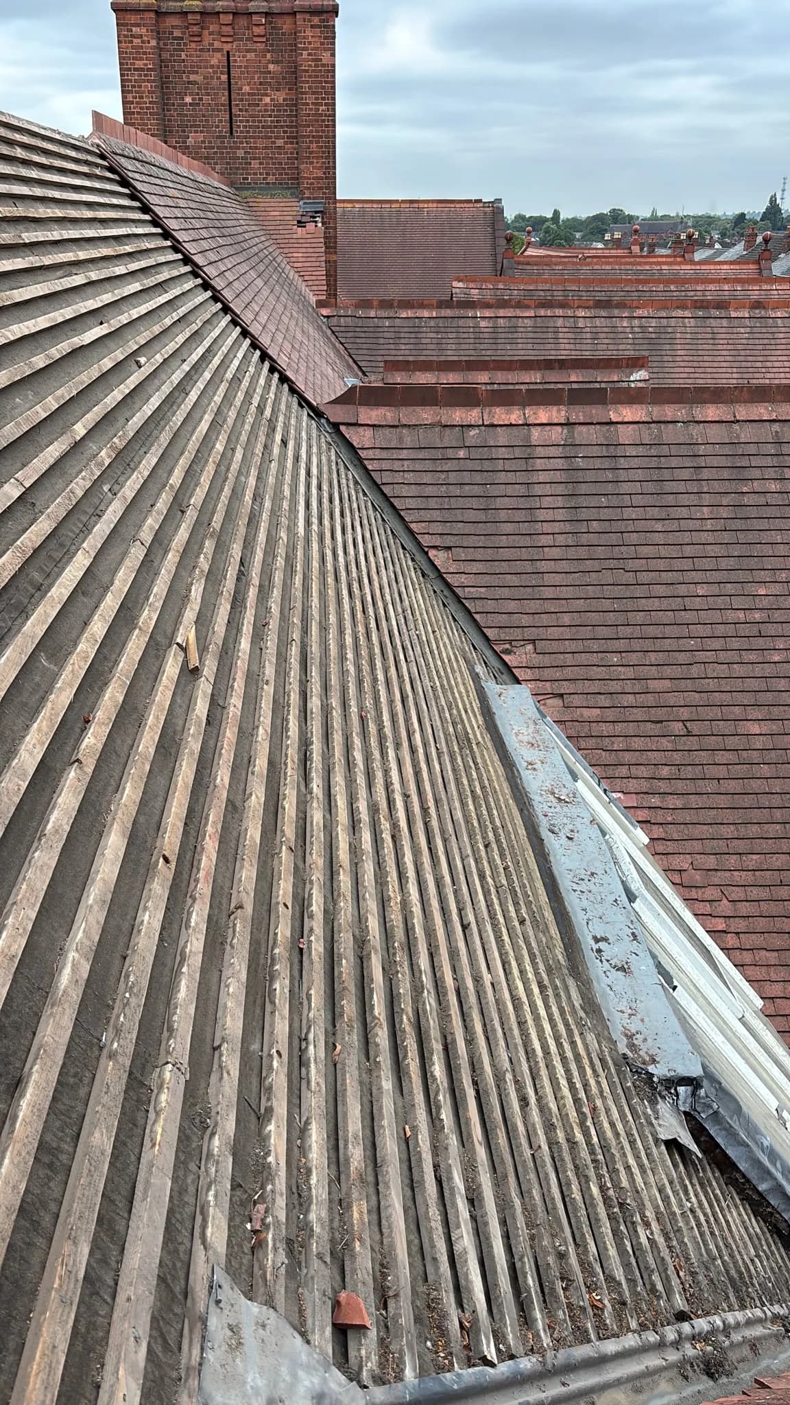 Grey slate roof ridge with houses in the background