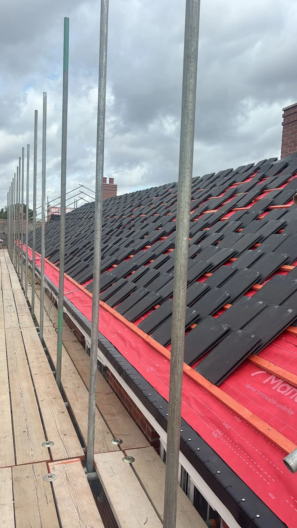 Grey slate roof with fresh underlay and edge scaffolding